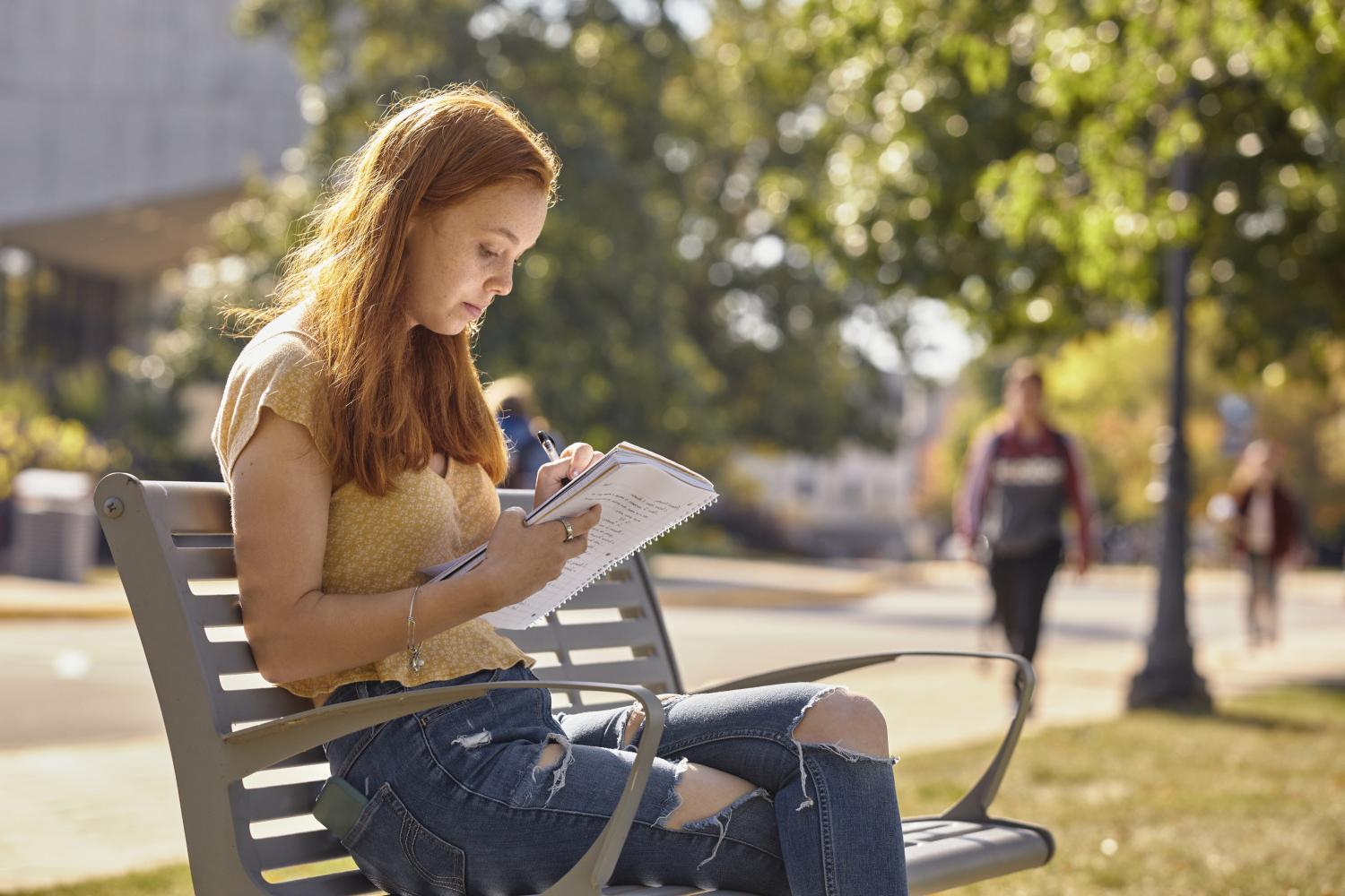 A <a href='http://uplz.vivendaoriente.com'>全球十大赌钱排行app</a> student reads on a bench along Campus Drive.